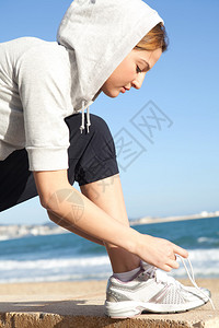 沙滩上运动妇女弯腰绑鞋带图片