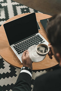商人喝咖啡和看笔记本电脑的图片
