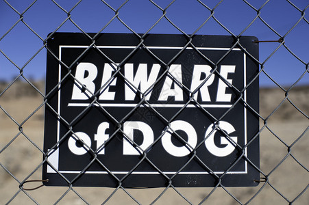 当心门后的狗标志背景图片