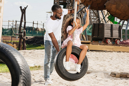 AfricanAmericandaughter在游乐园的轮胎摆动上展图片