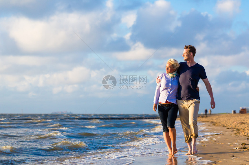 情侣在德国北海边的沙滩和海浪中走过一图片