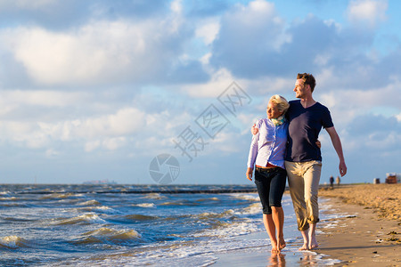 情侣在德国北海边的沙滩和海浪中走过一图片