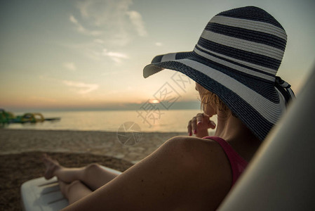 单身妇女坐在沙滩的椅图片