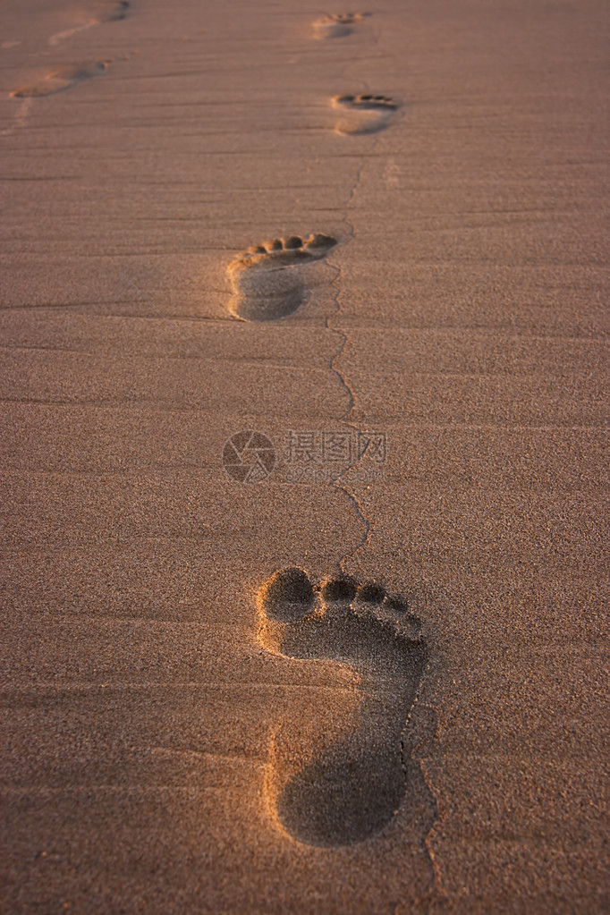 日落时海滩上的脚印旅游度假背景图片