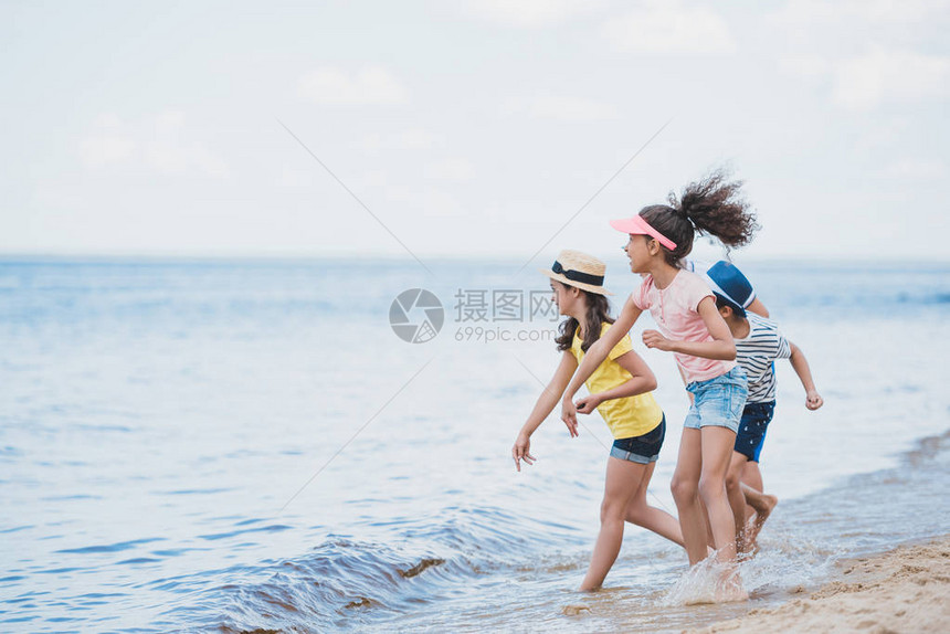 多文化儿童一起向海边投掷石图片
