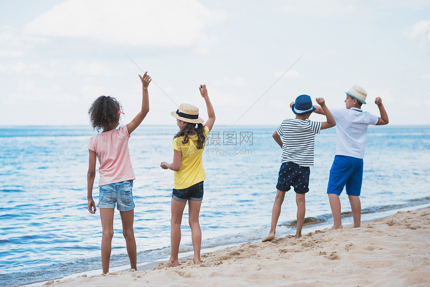 一群孩子一起在海边扔石头的背影图片