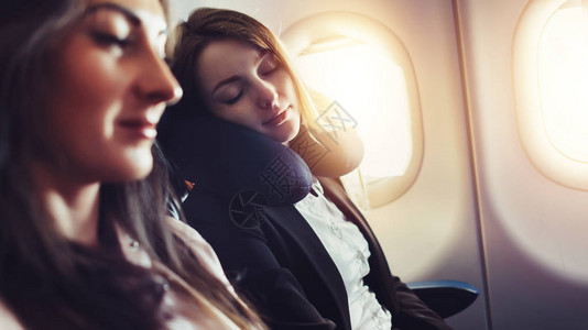 一名女乘客睡在飞机的颈垫上坐在飞机图片