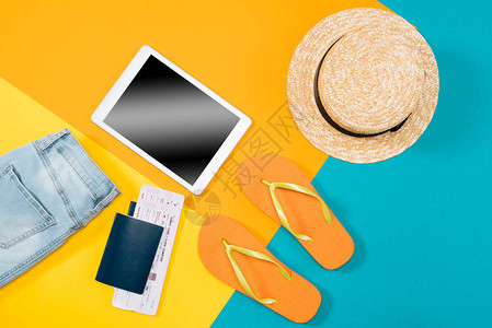橙色翻转花护照机票数字平板电脑和彩色背景衣服的顶端视图基本假期项目图片