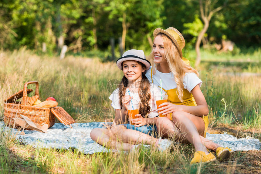 母亲和女儿在野餐时坐在毯子上图片