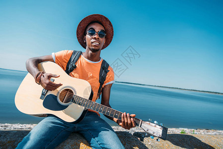 坐在地毯上弹吉他和演奏吉他的非洲图片