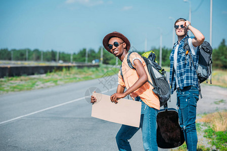 有空纸板的多种族多裔青年男子在旅行途中搭便图片