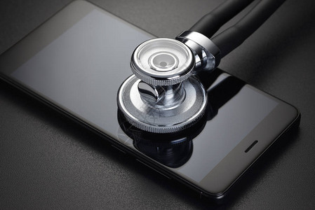 黑色背景上的听诊器和智能手机电话维修或在线医疗图片
