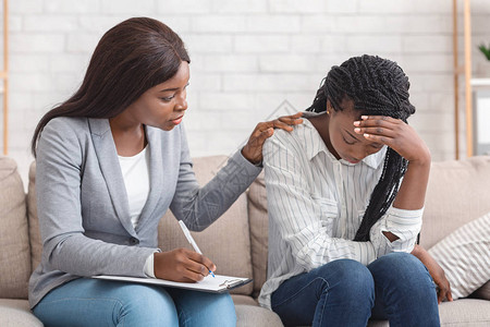 女心理学家在办公室治疗期间安慰情绪压抑的黑人妇女图片
