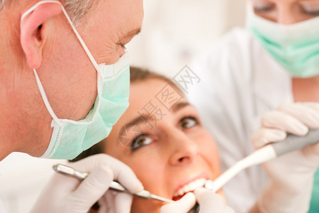 牙科治疗期间的助理戴面罩和手套佩戴图片