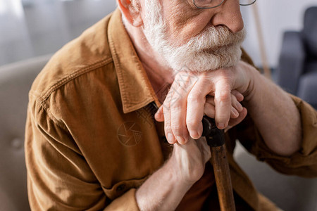 坐在和靠着拐杖的低压老年男图片