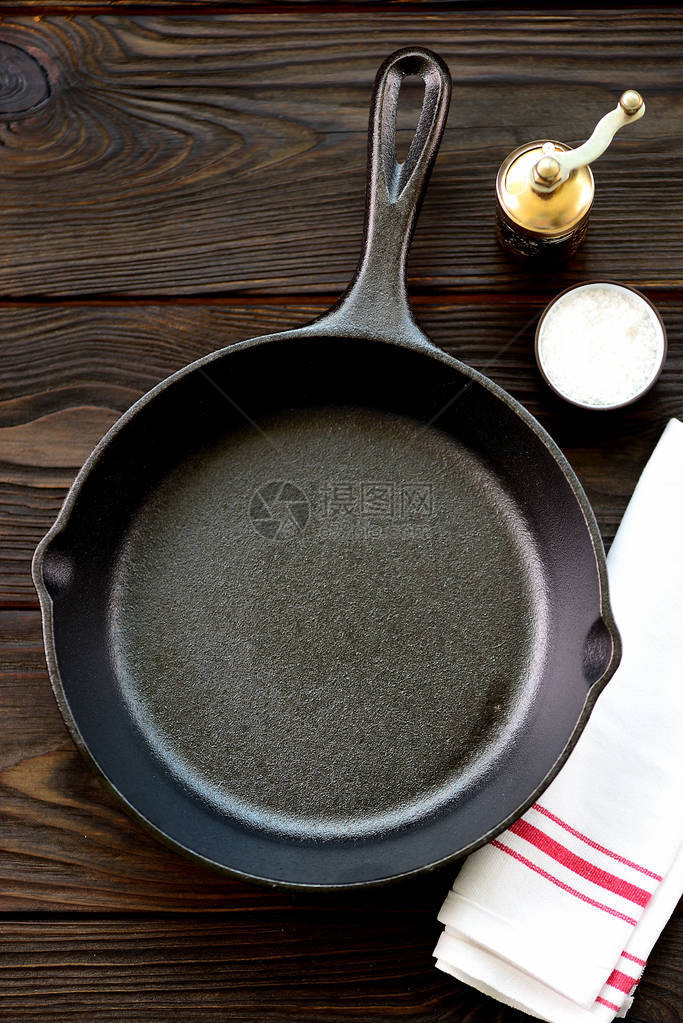 铸铁煎锅木制背景上加盐和胡椒图片