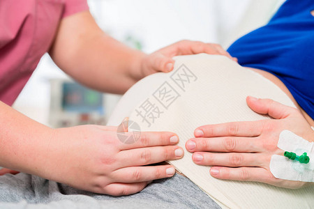 产房的助产士或护士对孕妇肚子背景图片
