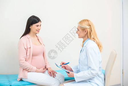 妇产科妇产科医生在诊所咨询孕妇并图片