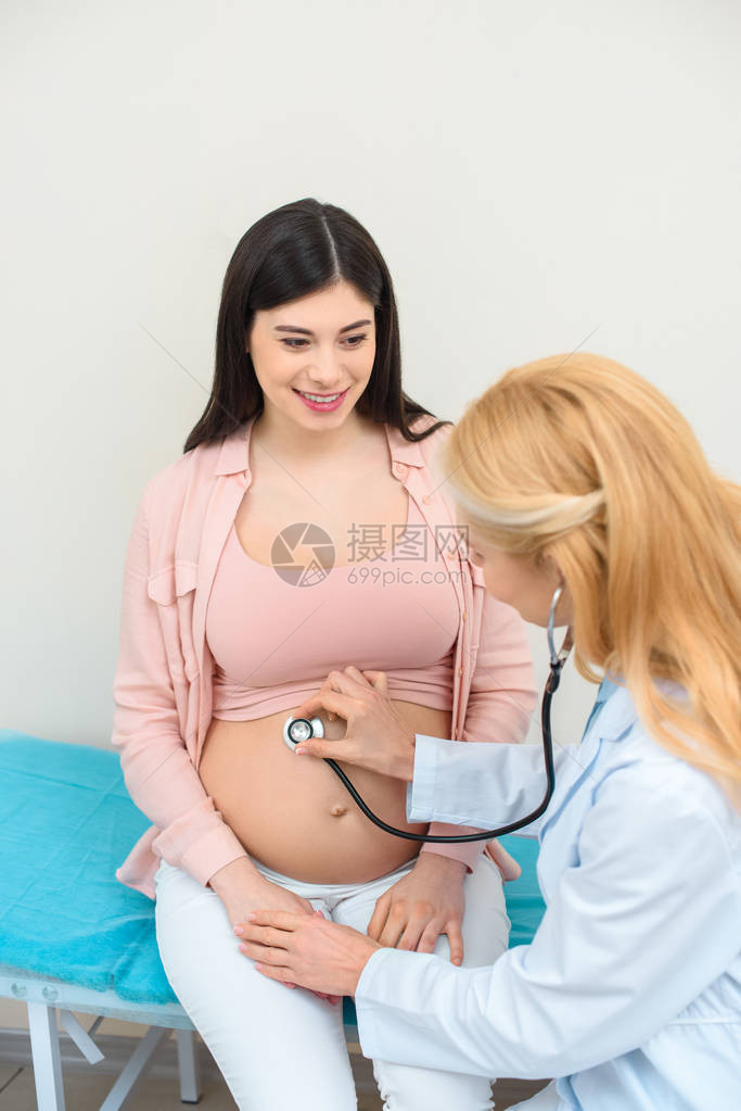 妇产科医生用听诊器听快乐孕妇胎儿的心跳图片