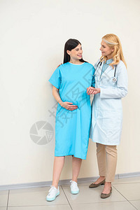 成熟的妇产科医生帮助孕妇走路图片