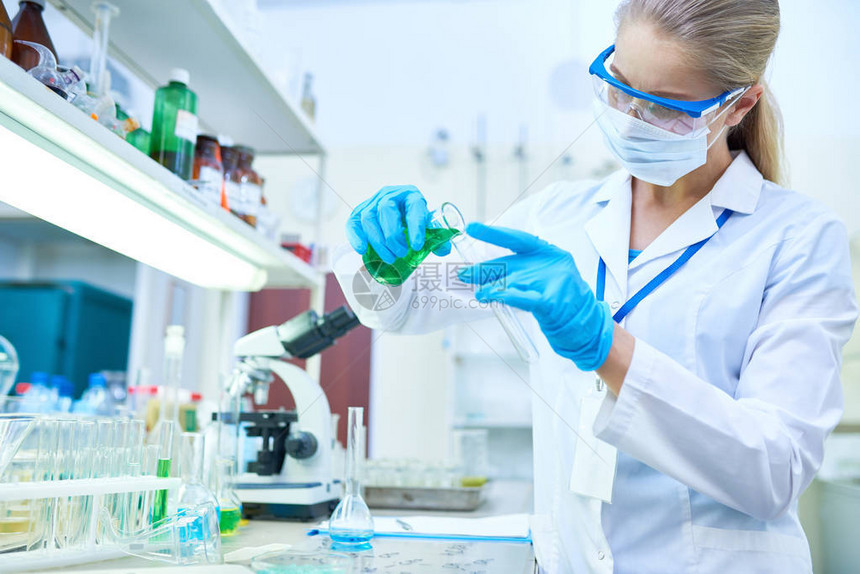 女科学家在医学实验室研究化学品时戴防护手套向试管倒彩图片