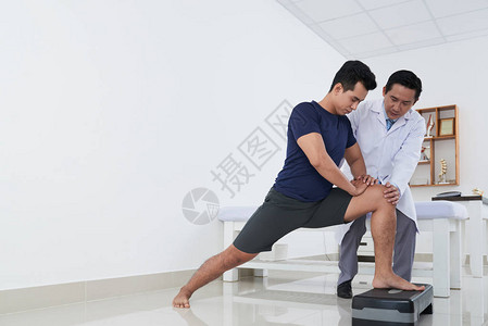 年轻的亚洲运动员在物理治疗师图片