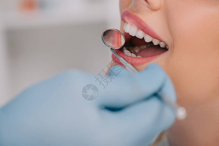 牙科医生用嘴镜检查年轻女子牙图片