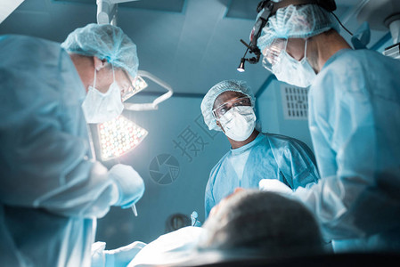 手术室内病人的多文化外科医生图片