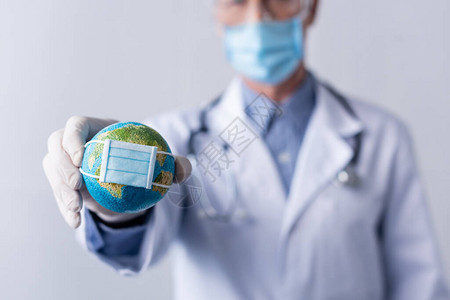 戴乳胶手套的成熟医生在灰色的医用面罩中手持小球图片