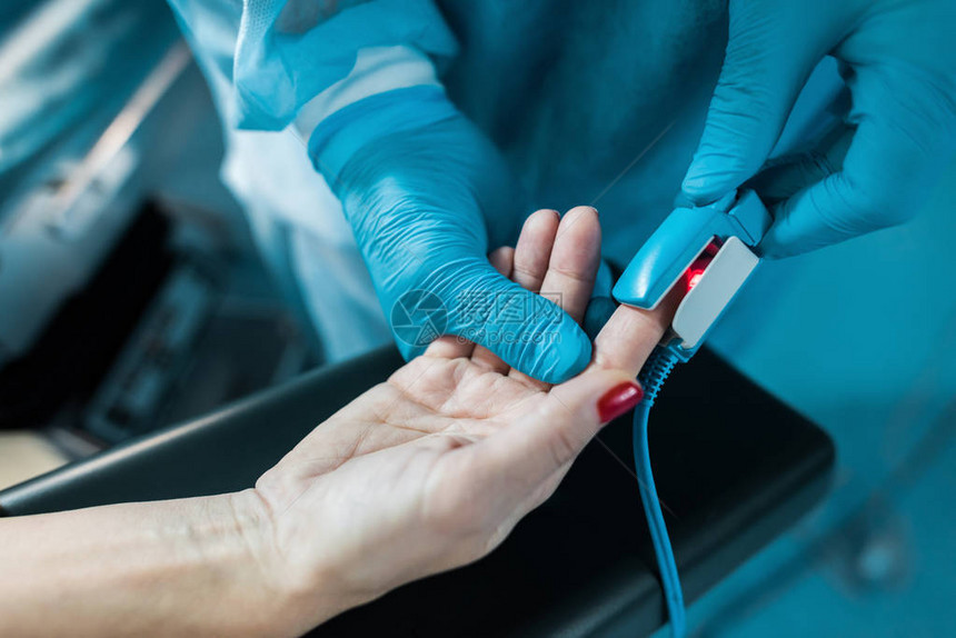 手术室病人手指上涂有脉冲血氧计的医生图片