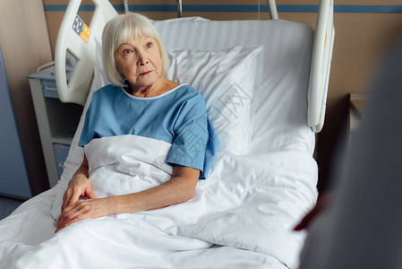 在医院床上躺着灰色头发的悲伤老年妇女有选择图片