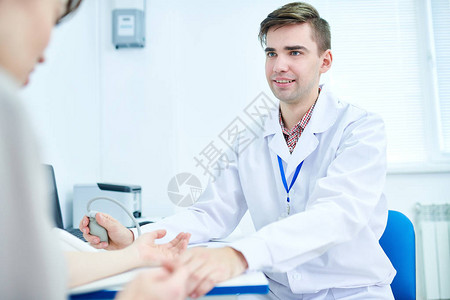 快乐的年轻医生在办公室用眼压计测量血压的肖图片