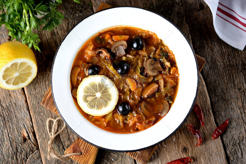 俄罗斯传统汤solyanka由菜新鲜和干燥的蘑菇以及橄榄柠图片