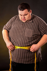 腹部脂肪和带子测量重下降的人在黑背景的全身第一天饮食图片