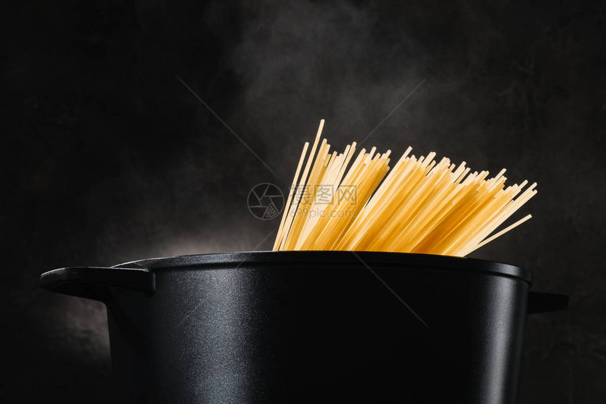 在深色背景下的黑锅里煮意大利面图片