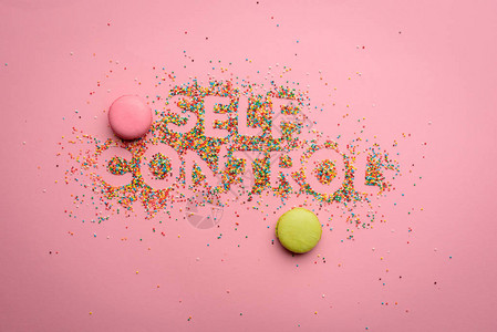由孤立于粉红色健康生活概念上的糖果制成的自我控制字母图片