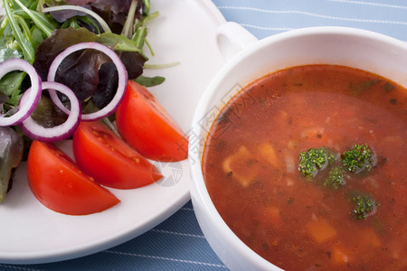 矿泉汤和一份配有绿洋葱和番茄的沙拉图片