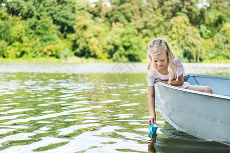 快乐的小孩在湖上漂浮在船上时发背景图片