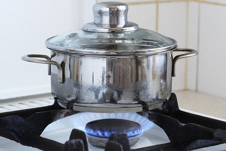 站在厨房炉灶上烧火的金属烹饪锅使用其他背景的图片