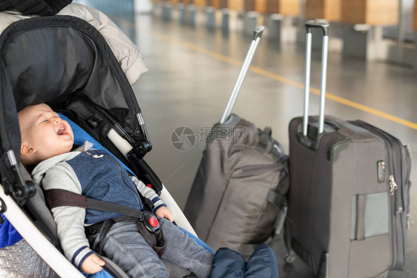 尖叫的男婴坐在机场航站楼行李附近的婴儿车里登机柜台附近的马车里的孩子孩子们流泪恐慌和歇斯底里带着小图片