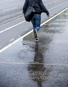 带着书包在雨中奔跑的年轻女子图片