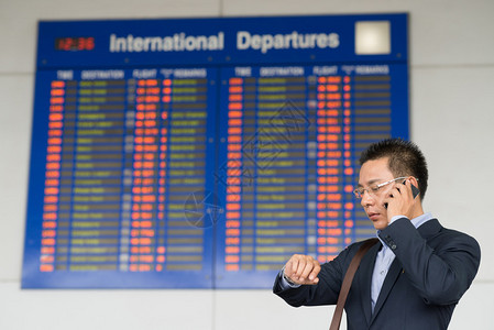 越南商人在接近飞行时间表时通过电话交谈和检查时间图片