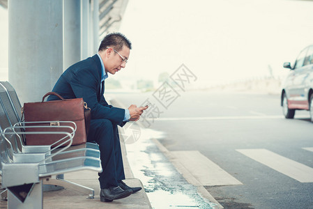 坐在机场公交站的高级商人图片