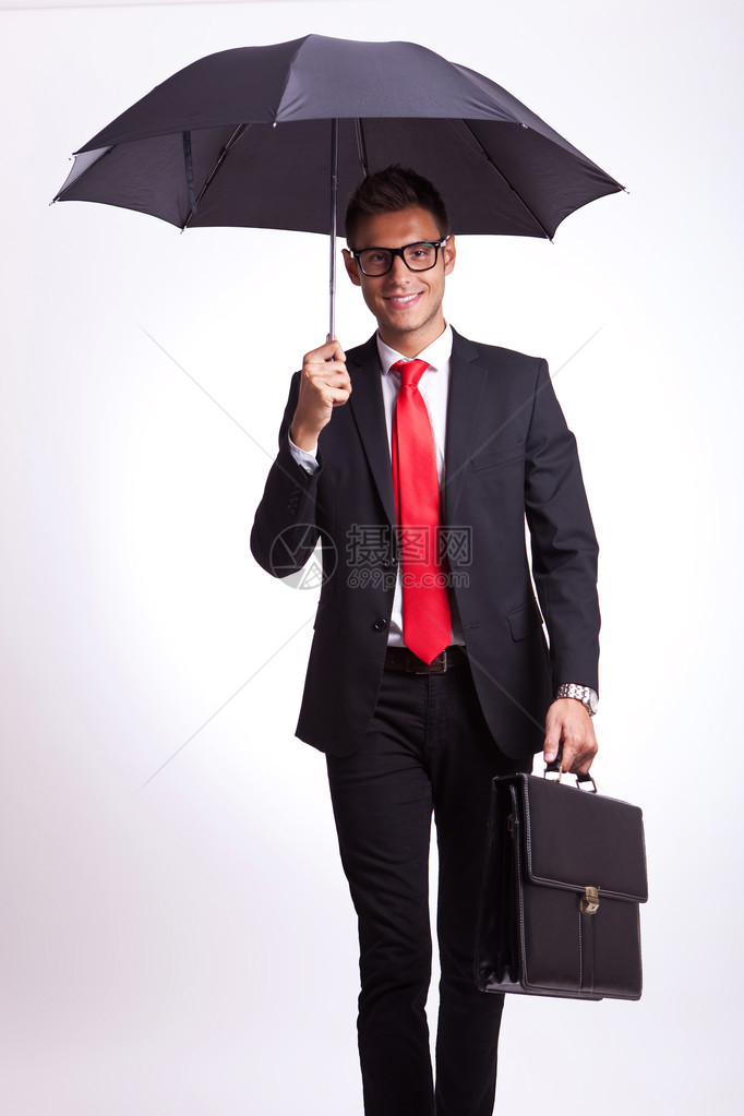 坐在伞下笑着的商人在灰色背景图片