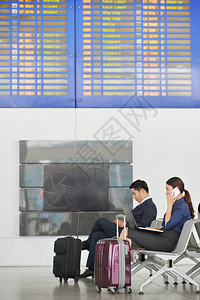 现代亚洲商人在机场用大手提箱的图片