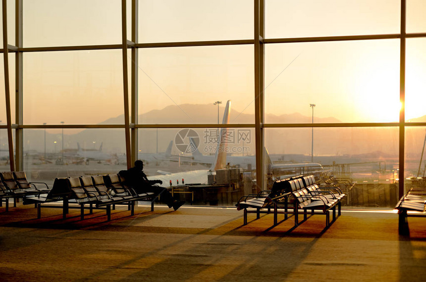 坐在大厅机场等待飞行的乘客使用手机在休图片