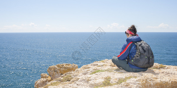 坐在海边悬崖上的女人背景图片