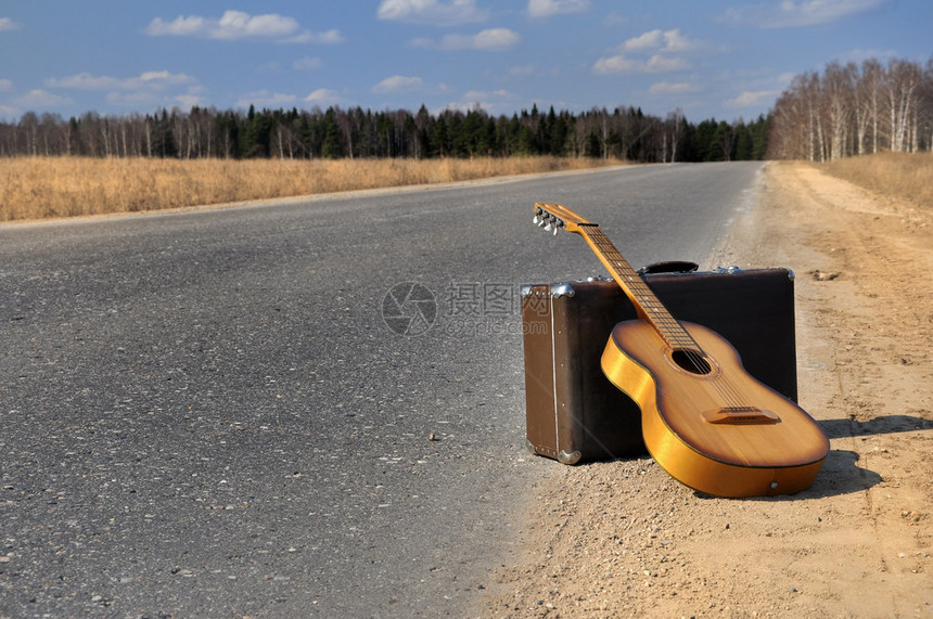 行李和吉他躺在空荡的乡间小路上图片