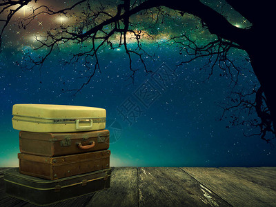 木板上堆积的皮革行李和夜空中的星旅行概图片