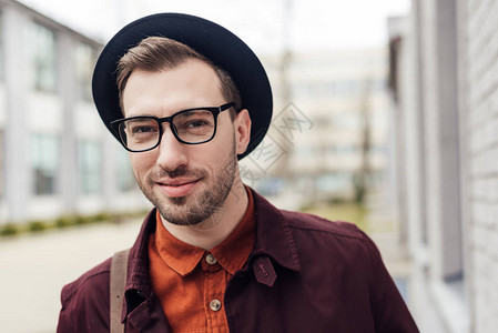 戴着时髦帽子和眼镜的英俊微笑的年轻人图片